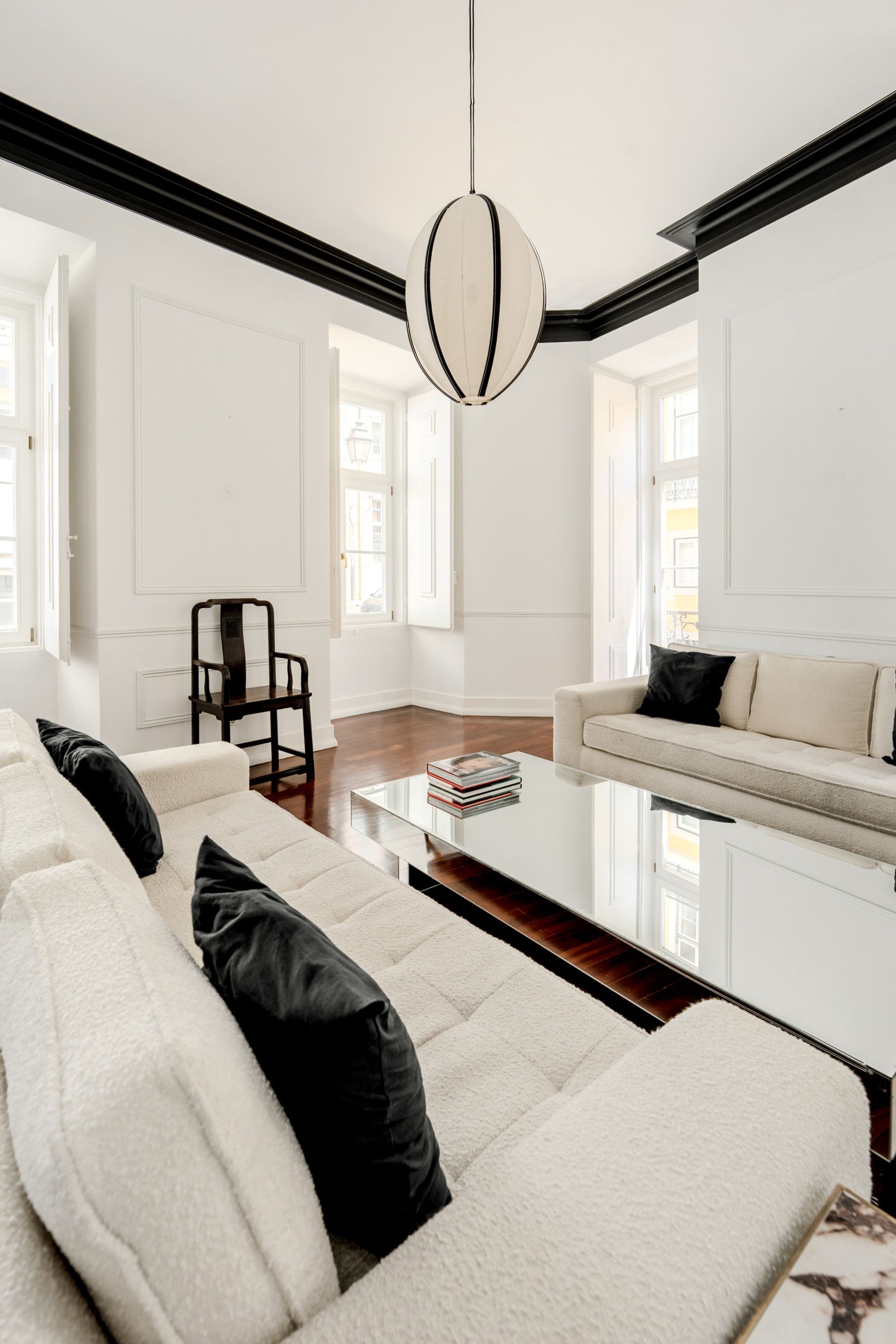 A modern living room with a sofa, a coffee table, and a hanging light fixture.