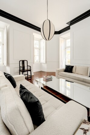 A modern living room with a sofa, a coffee table, and a hanging light fixture. - Chiado Deluxe by Homing (Lisbon)
