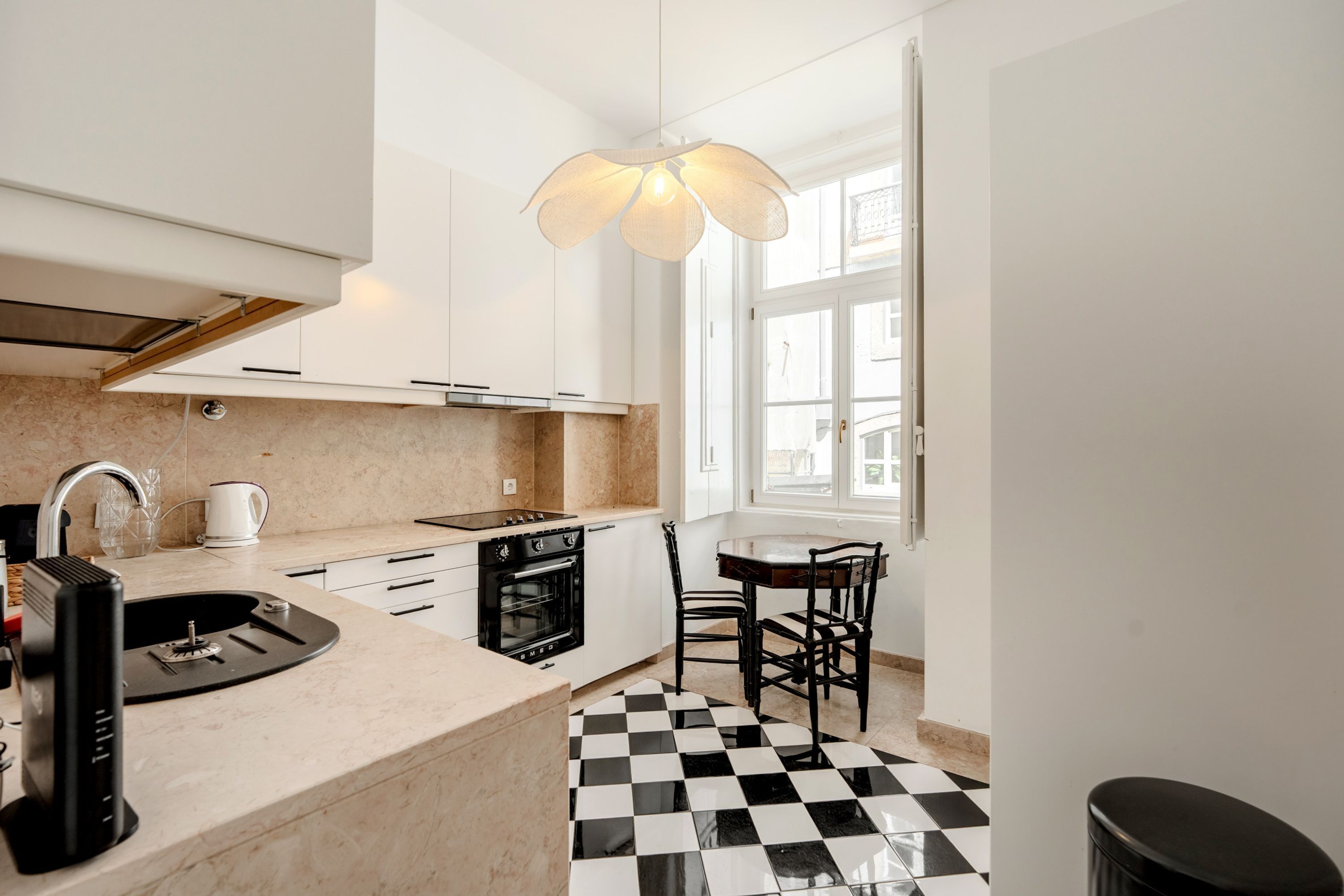 Een moderne keuken met een geruit vloertje, een koffieapparaat en een eethoek met stoelen.