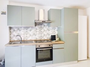 A compact kitchen with a built-in oven, a stainless steel sink, and light-colored cabinets. - La Tana by Interhome (Castiglioncello)