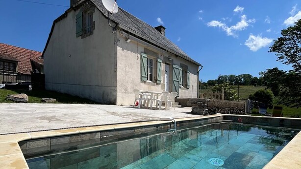 Ein Haus mit Swimmingpool, Satellitenschüssel und Steinmauer.