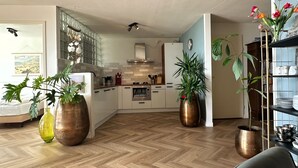 A modern kitchen with herringbone flooring, a central island, and a dining area with a sofa. - Beautifully located on Nordboulevard on the 1st floor. Directly on the beach, balcony with wonderful sea view, 2 bedrooms and garage. (Egmond aan Zee)