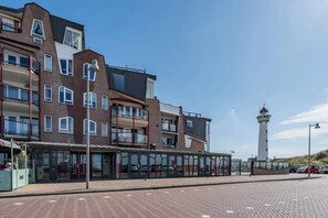 Ein modernes Gebäude mit mehreren Stockwerken, einer Glasfassade und einem Leuchtturm im Hintergrund.