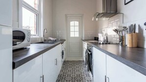 Una cocina pequeña con lavadora, microondas y cafetera.