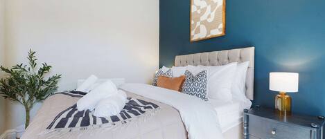 A neatly made bed with a striped blanket, a bedside lamp, and a nightstand with drawers.