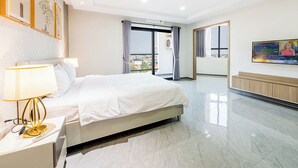 A hotel room with a bed, bedside table, lamp, and a TV on the wall. - H Resident (Phnom Penh)