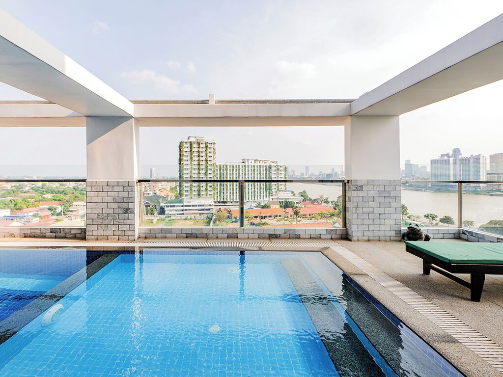 A rooftop swimming pool with a view of a cityscape and a river.