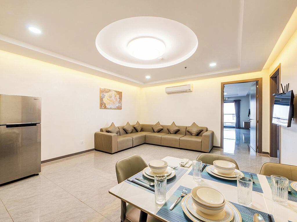 Un comedor moderno con una lámpara redonda en el techo, un sofá y una mesa de comedor preparada para cuatro comensales.