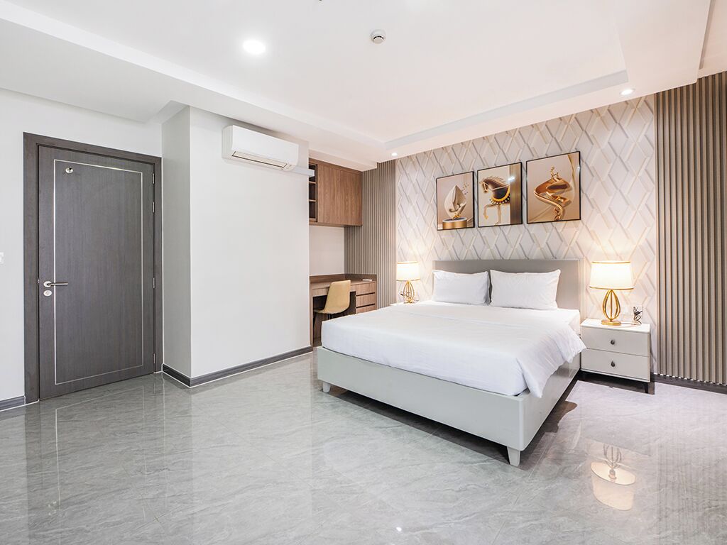 Une chambre d’hôtel moderne, dotée d’un grand lit, de tables de chevet, d’une armoire et d’un climatiseur fixé au mur.
