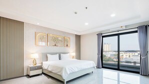 A modern hotel room with a large bed, bedside tables, a city view, and a large window with curtains. - H Resident (Phnom Penh)
