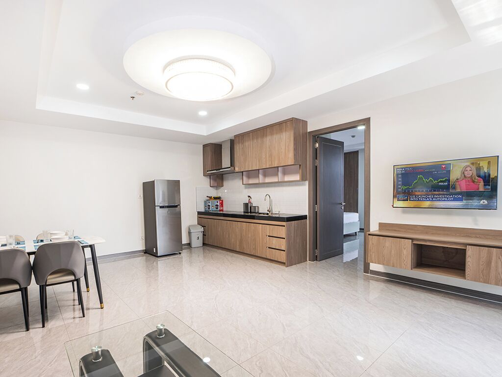 A modern kitchen with a built-in oven, a refrigerator, and a dining area with chairs and a table.