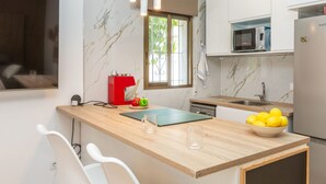 Une cuisine moderne avec un dosseret en marbre, un four à micro-ondes encastré, une machine à café rouge et un bol de citrons posé sur le comptoir.