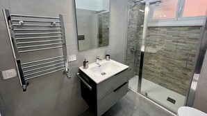 Ein modernes Badezimmer mit Duschkabine aus Glas, integriertem Waschbecken und Handtuchhalter.