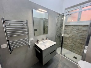 Ein modernes Badezimmer mit Duschkabine aus Glas, integriertem Waschbecken und Handtuchhalter.