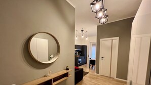 Ein modernes Interieur mit einem runden Spiegel, einem Holzregal und einem Flur, der in einen Essbereich führt.