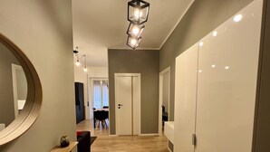 Ein Flur mit Holzboden, einem Spiegel, einer Bank und einer Tür zu einem Zimmer.