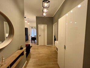 Ein Flur mit Holzboden, einem Spiegel, einer Bank und einer Tür zu einem Zimmer.