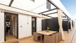 Eine moderne Terrassenanlage mit Tisch, Stühlen und einem Blumentopf.