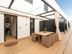 Eine moderne Terrassenanlage mit Tisch, Stühlen und einem Blumentopf.
