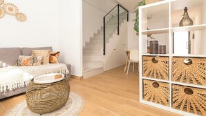 Ein stilvolles Wohnzimmer mit Sofa, Couchtisch, Treppe und einer dekorativen Regalanlage.