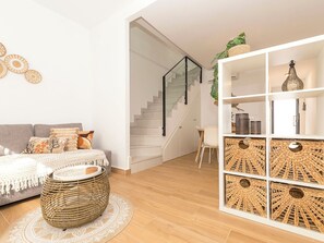 Ein stilvolles Wohnzimmer mit Sofa, Couchtisch, Treppe und einer dekorativen Regalanlage.