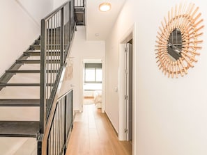 Eine Treppe mit Metallgeländern, ein Flur mit Holzboden und ein dekorativer Wandspiegel.