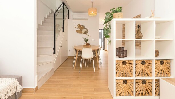 Ein modernes Interieur mit Treppe, Essbereich und einem weißen Regal mit gewebten Körben.