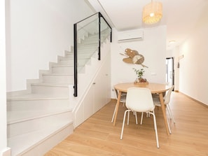 Ein modernes Interieur mit einer Treppe, einem Essbereich mit rundem Tisch und Stühlen sowie einem dekorativen Wandkunstwerk.