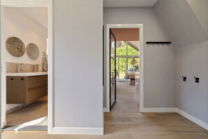 Un pasillo con suelo de madera, una cocina con armarios de madera y un comedor con sillas y una mesa.