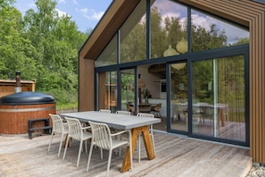 A modern house with a deck, a large dining table, and a barbecue grill. - A cosy bungalow for four people with its own hot tub, situated in the green heart of Drenthe amongst the woods of Gasselte (Gasselte)
