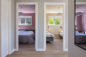 A bedroom with two beds, a window, and a mirror. - A cosy bungalow for four people with its own hot tub, situated in the green heart of Drenthe amongst the woods of Gasselte (Gasselte)