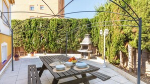 Ulkoterassi, jossa on puinen ruokapöytä ja sen ympärillä metallinen pergola.