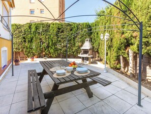 Eine Terrasse im Freien mit einem Holztisch, gedeckt für das Essen, umgeben von einer Metallpergola.
