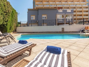 Ein Poolbereich mit Liegestühlen und einem Gebäude im Hintergrund.