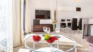 Un salon moderne avec une table en verre, un téléviseur et un coin repas.