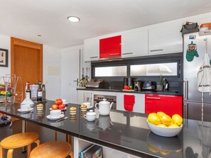 Eine moderne Küche mit schwarzem Arbeitsplatz, Edelstahlgeräten und roten Akzenten.
