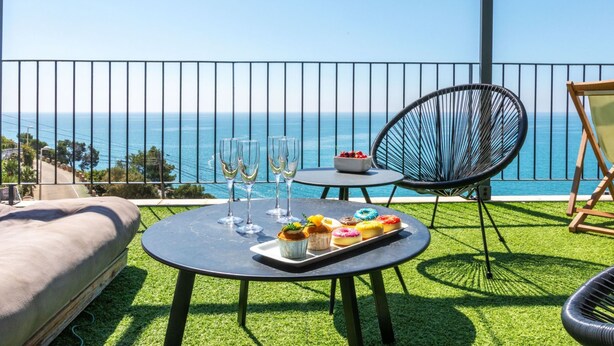 Un balcón con una mesa para dos, una silla y vistas al mar.