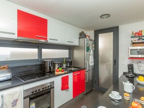 Eine moderne Küche mit Herd, Backofen, Kühlschrank und Mikrowelle.
