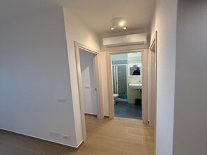 A hallway leading to a bathroom with a visible toilet, sink, and a person in the mirror. - Sea view escape at Lido dei Pini (Bibione)