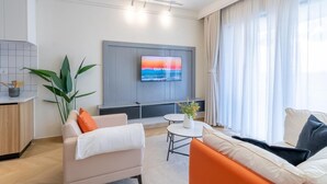 Una sala moderna con televisor, sofá y zona de comedor.