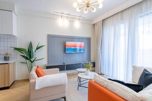 Ein modernes Wohnzimmer mit Fernseher, Sofa und Essbereich.