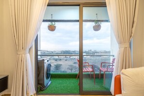 Ein Balkon mit Waschmaschine, zwei roten Stühlen und Blick auf eine entfernte Landschaft.