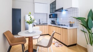 Cocina compacta con mesa, sillas, refrigerador y cafetera.