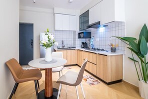 Eine kleine Küche mit Esstisch, Stühlen, einem Kühlschrank und einer Kaffeemaschine.