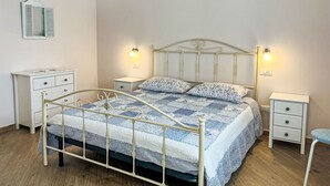 Um quarto com uma cama, duas mesas de cabeceira, um criado-mudo e um espelho.