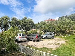 A parking area with three cars, surrounded by greenery and a building in the background. - Pierina by Interhome (Finale Ligure)