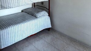 A bunk bed with striped bedding in a room with a tiled floor and a plain wall. - Small villa in quiet setting a few minutes from the sea (Villasimius)