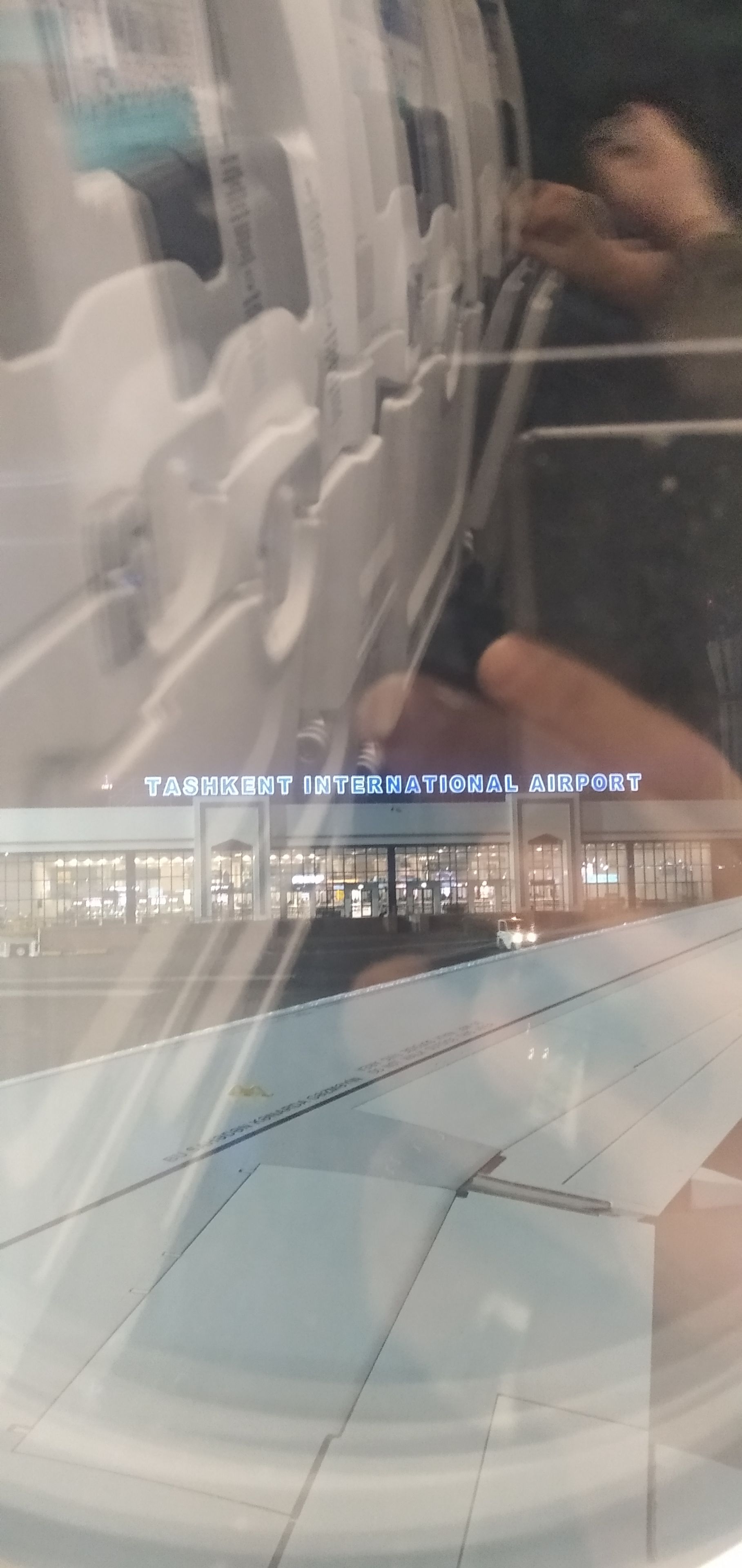 Ein Flughafen-Terminal mit freiem Blick auf den Innenbereich und eine Schilder mit dem Aufdruck 'Tashkent International Airport'.