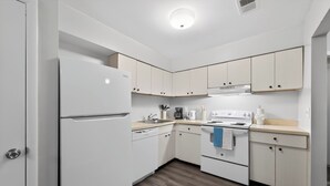 Uma cozinha compacta com eletrodomésticos brancos, armários de madeira e painel de azulejos.