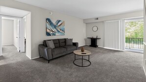 Uma sala de estar moderna com um sofá cinzento, uma mesa de centro redonda e um quadro abstrato grande na parede.